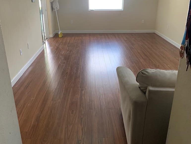 Living laminate medium brown planks armchair foreground sliders medals hanging wall beige paint white baseboard glossy.