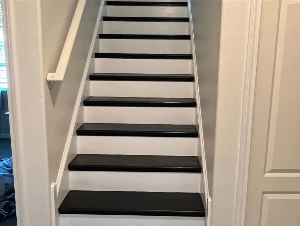 Straight stairs black stained tread surfaces white painted risers light grey walls symmetrical upward photo interior.
