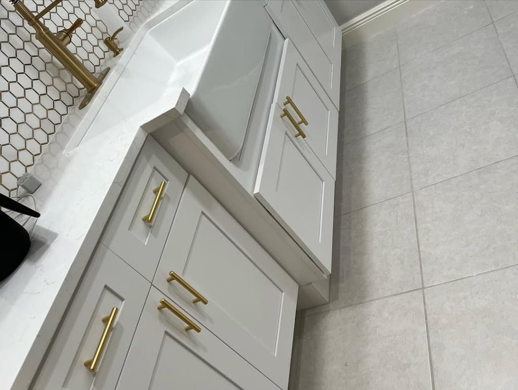 Close gold fixtures white apron sink metallic hex backsplash white shaker lowers gold pulls perspective corner kitchen.