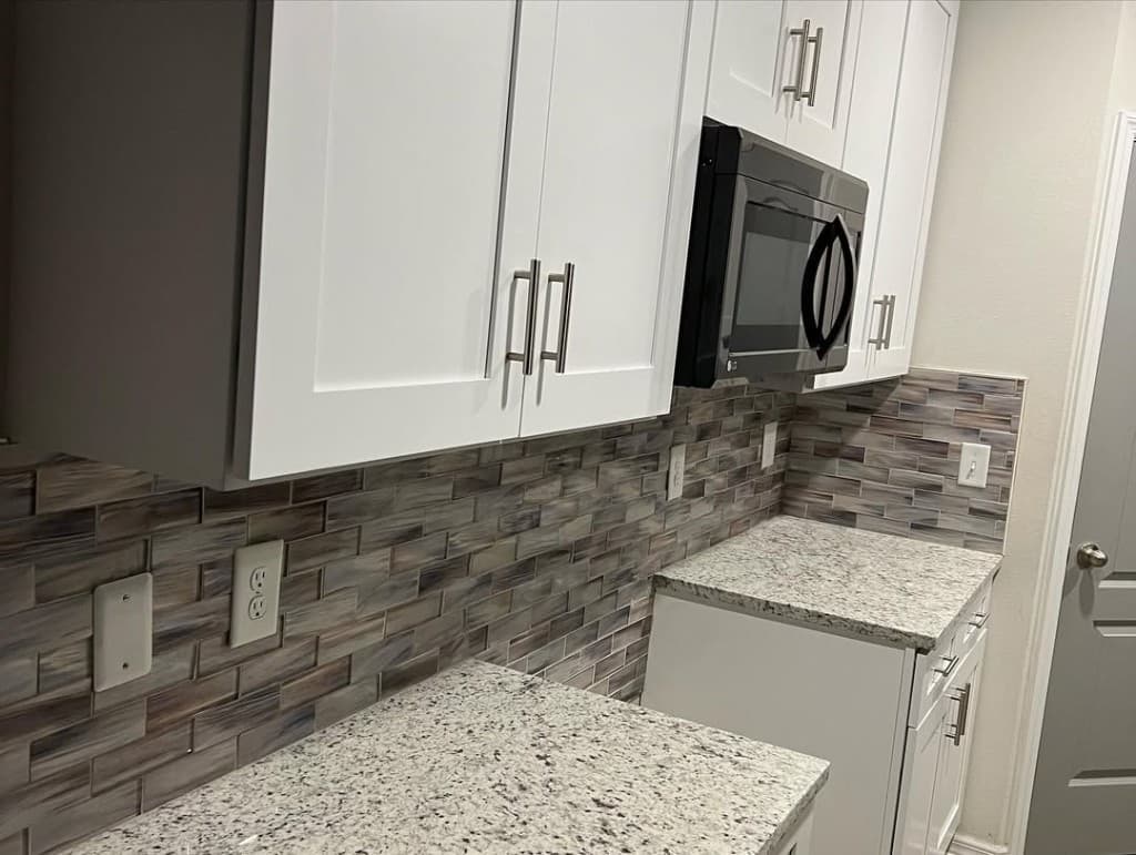 Close shaker cabinet mosaic stacked horizontal rectangles speckled granite black microwave knob hardware silver nickel.