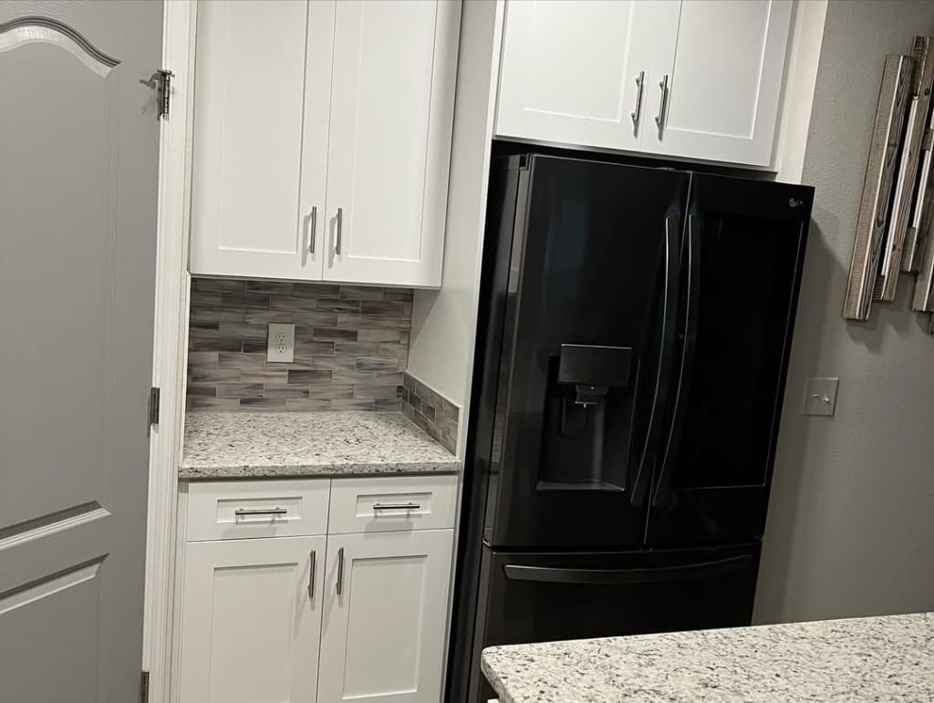 Kitchen cabinetry white subway brown grey stacked mosaic black refrigerator panel arch door left crown trim.