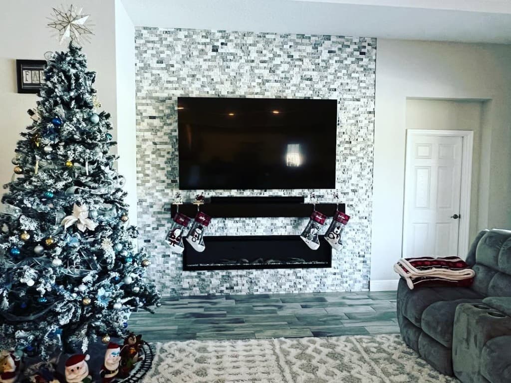 Living ledger stone accent wall mounted TV stocking mantel flocked christmas tree plush rug modern electric fireplace flames.